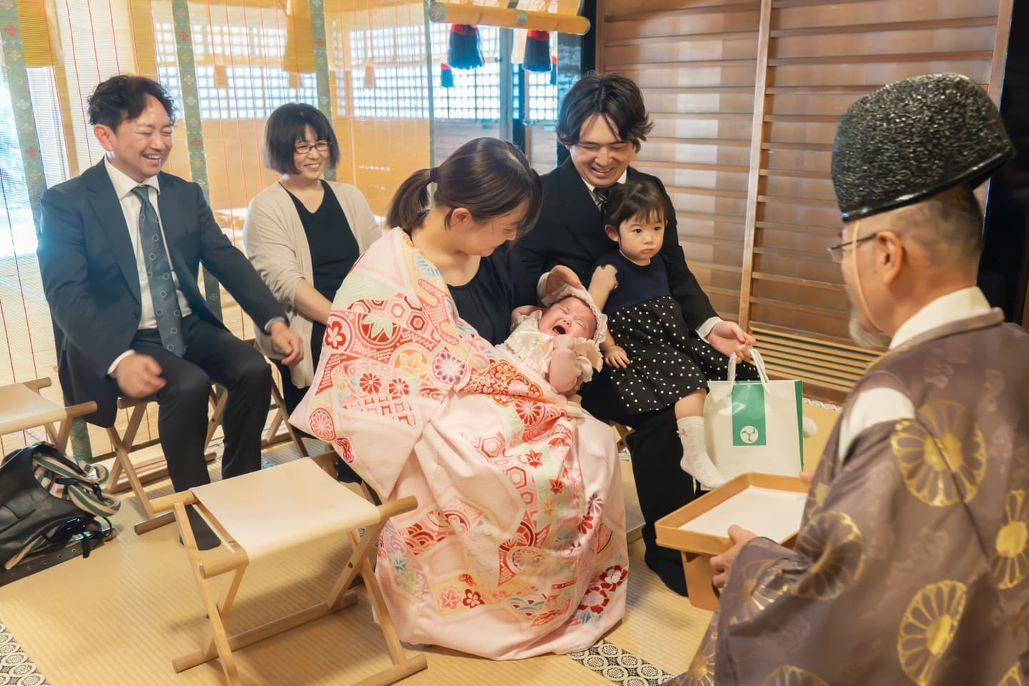 代々木八幡宮のお宮参りのご祈祷で神職からお札を授かるご家族の写真